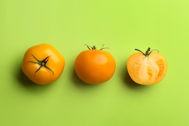 Yellow tomatoes on green background, flat lay