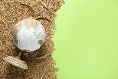 Globe and grains on light green background, top view. Hunger crisis concept