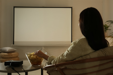 Young woman watching movie using video projector at home