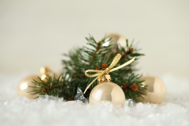Beautiful Christmas balls and fir branch on snow against white background