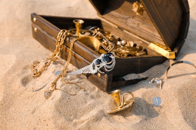Open wooden chest with treasures on sand