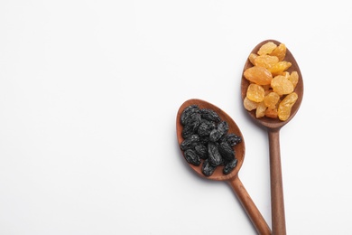 Spoons with raisins and space for text on white background, top view. Dried fruit as healthy snack