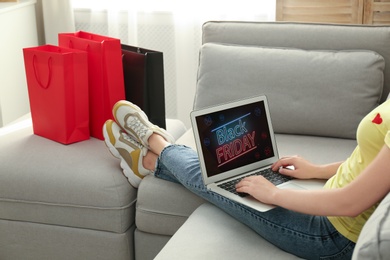 Woman using laptop with Black Friday announcement on screen, closeup