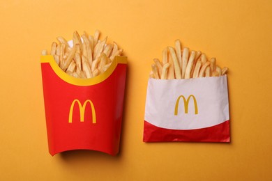 MYKOLAIV, UKRAINE - AUGUST 12, 2021: Small and big portions of McDonald's French fries on orange background, flat lay