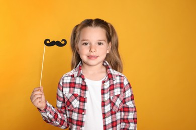 Photo of Little girl with fake mustache on yellow background