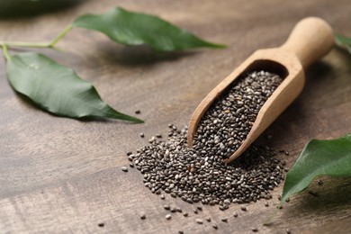 Photo of Scoop with chia seeds and fresh leaves on wooden table, space for text