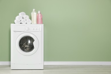 Photo of Empty laundry room with washing machine and detergents, space for text. Interior design