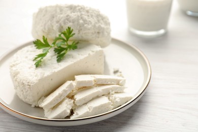 Delicious fresh cottage cheese with parsley on white wooden table, closeup
