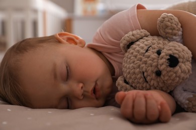 Adorable little baby with toy bear sleeping on bed at home, closeup
