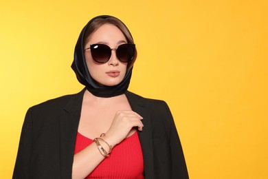 Young woman with lip piercing and sunglasses on yellow background. Space for text