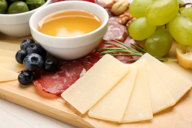 Snack set with delicious Parmesan cheese on wooden board, closeup