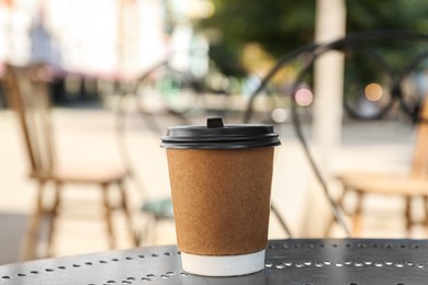 Photo of Paper cup on table in outdoor cafe. Takeaway drink