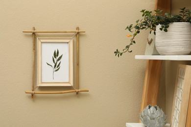 Green plant on shelving unit near beige wall with bamboo frame