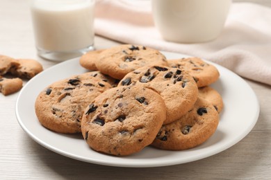 Plate with delicious chocolate chip cookies on white wooden table, closeup