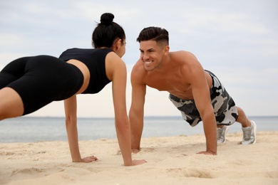 Couple doing exercise together on beach. Body training
