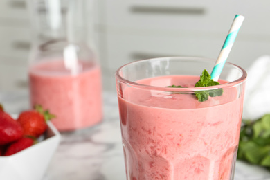 Tasty strawberry smoothie with mint in glass on table, closeup