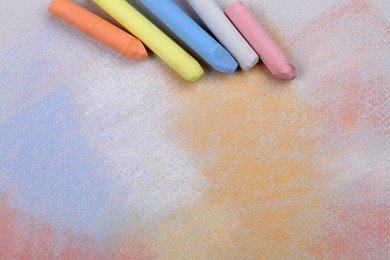 Colorful pastel chalks on abstract drawing, flat lay. Space for text