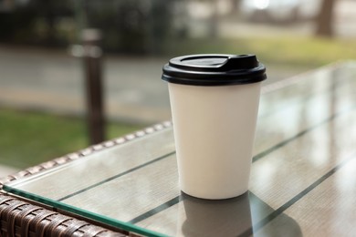 Paper takeaway cup on glass table outdoors. Coffee to go