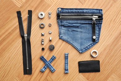 Flat lay composition with garment accessories and cutting details for jeans on table