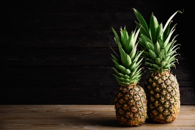 Fresh ripe juicy pineapples on wooden table. Space for text
