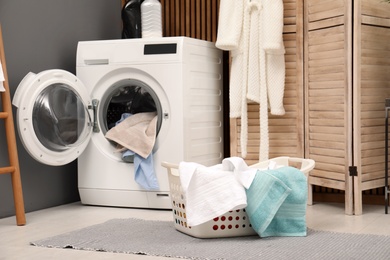 Basket with dirty towels on washing machine in modern laundry room