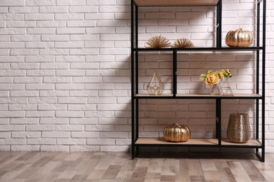 Shelving with different decor near white brick wall, space for text. Interior design