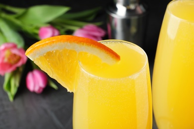 Glass of Mimosa cocktail with garnish on grey table, closeup