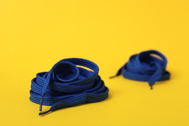 Blue shoe laces on yellow background. Space for text