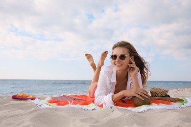 Beautiful woman lying on beach towel near sea