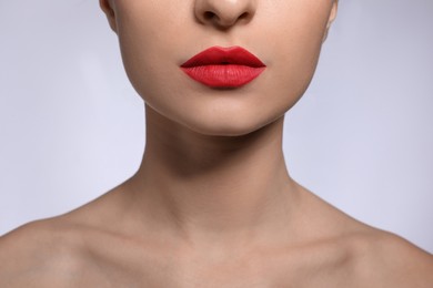 Young woman with beautiful lips makeup on light background, closeup