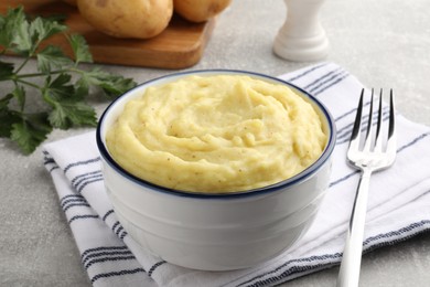 Photo of Bowl of tasty mashed potatoes served on grey table