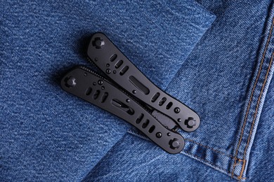 Modern compact portable multitool on denim fabric, top view