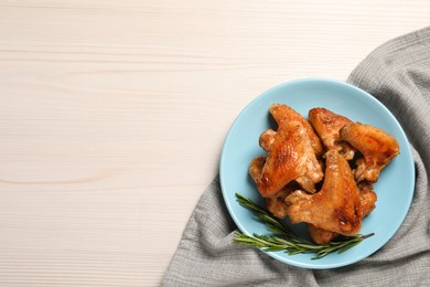 Photo of Plate with delicious fried chicken wings and sprig of rosemary on white wooden table, top view. Space for text