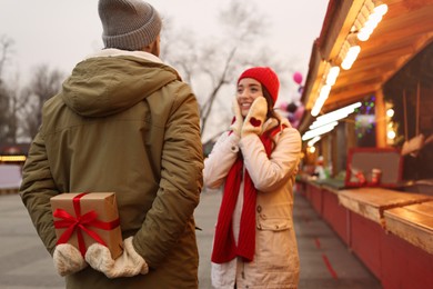 Lovely couple at winter fair, focus on Christmas present