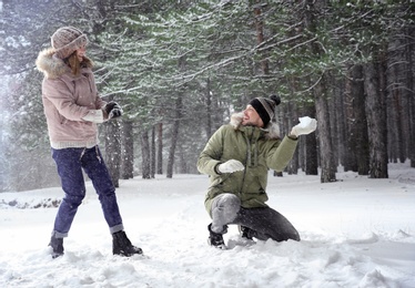 Happy couple playing snowballs in winter forest