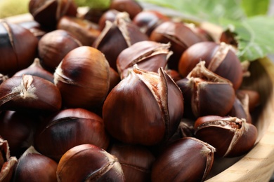 Delicious roasted edible chestnuts in wooden bowl, closeup