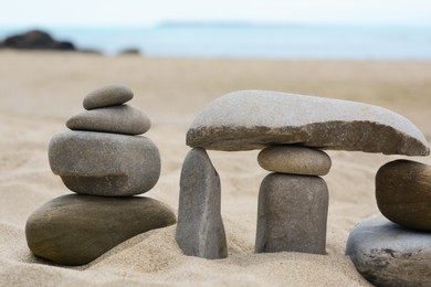 Stacks of stones on beautiful sandy beach near sea, closeup