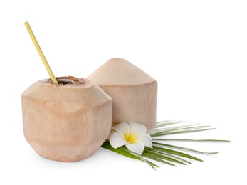 Young peeled coconuts with straw, palm leaf and beautiful flower on white background