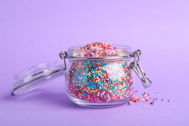 Colorful sprinkles in jar on lilac background. Confectionery decor