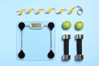 Flat lay composition with floor scales and dumbbells on light blue background. Weight loss concept