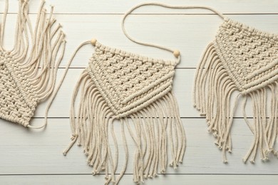 Stylish beige macrame on white wooden table, top view