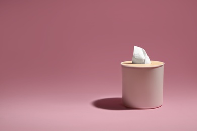 Holder with paper tissues on pink background. Space for text