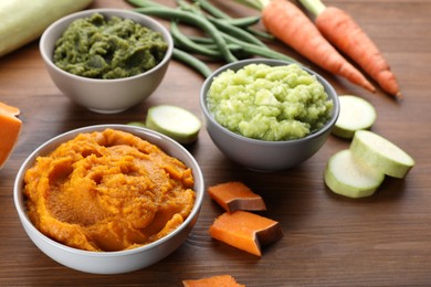 Tasty puree in bowls and ingredients on wooden table