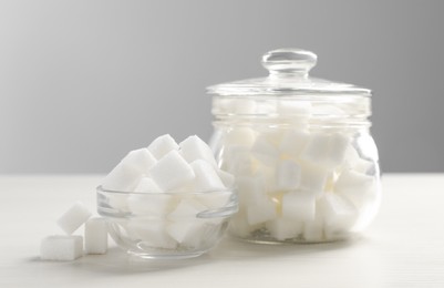 Glass jar and bowl with white sugar cubes on table