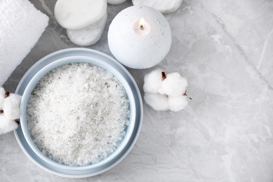 White sea salt and supplies for spa scrubbing procedure on grey marble table, flat lay
