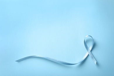 Blue ribbon on color background, top view. Cancer awareness