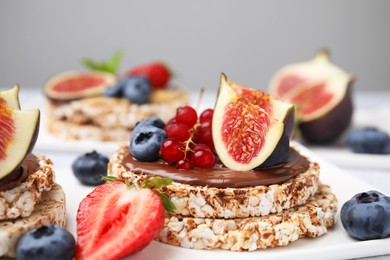 Tasty crispbreads with chocolate, figs and berries served on light table, closeup