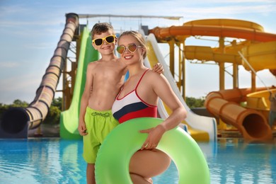 Son and mother with inflatable ring near pool in water park. Family vacation