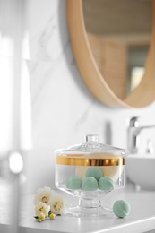 Jar with bath bombs and bath sponge on white countertop indoors