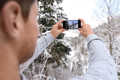 Photo of Man taking picture of snowy tree outdoors, closeup